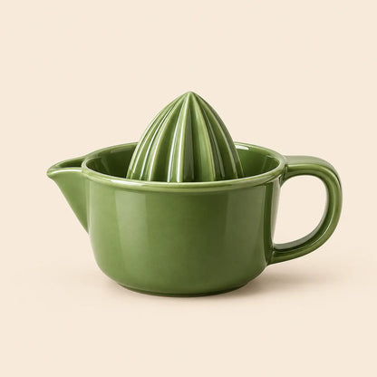 Verdelique olive green manual citrus juicer on a warm ivory background