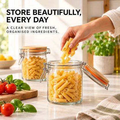 Open glass storage jar being filled with dry pasta in a bright modern kitchen